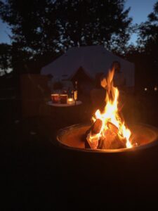 Kampvuur in de avond bij de Safari tent van B&B Erve Hasselo in Vorden. Oude achtergrond zie je een tafeltje met glazen wijn en versnaperingen en de tent.